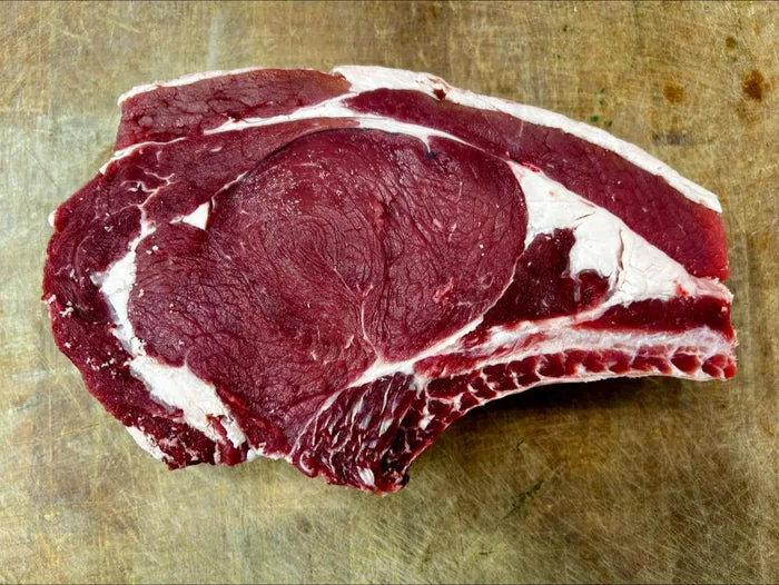 Raw bone-in beef steak on a wooden board
